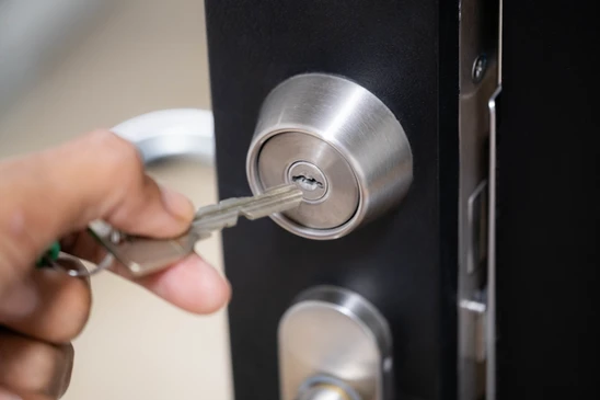 Mains d'un serrurier installant une serrure de porte intérieure dans un environnement résidentiel aux murs blancs