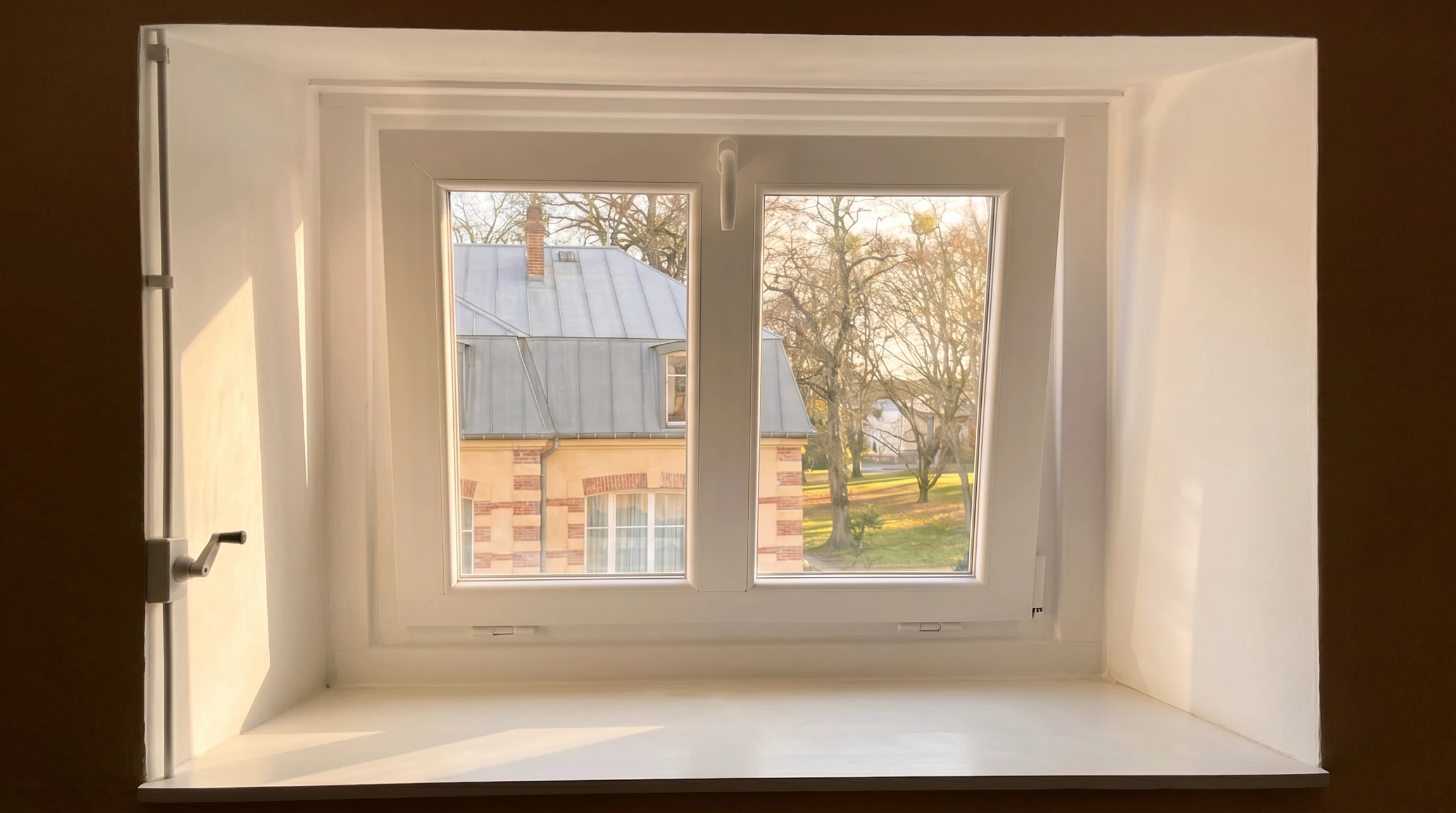 Intérieur moderne avec escalier descendant vers niveau inférieur, garde-corps en verre transparent, cuisine ouverte contemporaine au fond avec îlot central sombre
